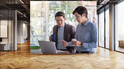 Two Asian businessman are meeting for a collaboration concept using a laptop  holding coffee  at the office. Wall mural