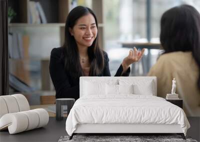 Two happy asian businesswoman talking and consulting working together in the office Wall mural