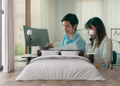 Two young Asian business people sitting together in the office. Two asian designer talking and development ux app on mobile phone during the meeting in office. Wall mural