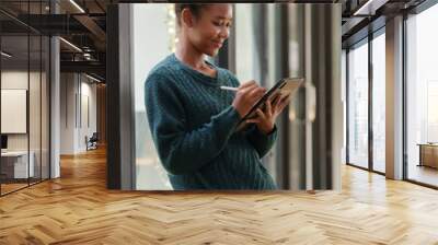 Woman student holding tablet preparing for online class. Wall mural