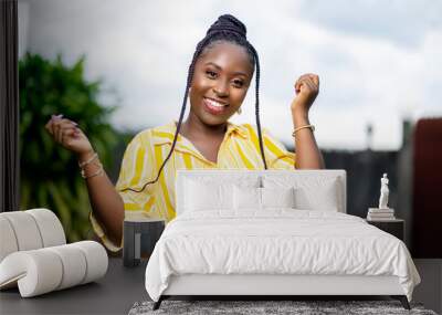 image of excited african lady outside- braided black woman laughing with both hands up Wall mural