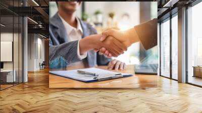 A young professional shaking hands with a new employer in an office setting. Wall mural