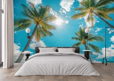 A stunning view of tall palm trees reaching towards a bright blue sky filled with fluffy clouds, evoking a perfect tropical getaway by the ocean. Wall mural