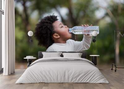 African American little girl drinking water while playing  in the park Wall mural