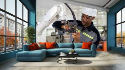 African American male engineer worker maintenance automatic robotic arm machine in factory. Black male technician worker checking, repair automatic robot hand machine with screwdriver in smart factory Wall mural