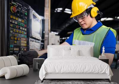 Asian engineer male worker maintaining electronics of machine at the industry factory. Factory worker check or maintenance CNC machine in industry factory Wall mural