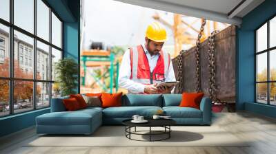 Asian male construction working at construction site. Male engineer working with digital tablet. Male engineer construction wear safety uniform and helmet at construction site Wall mural