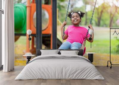 Cute African American little girl playing on swing. Smiling child playing in summer in the park. Kid in the field trips outdoor, Freedom, Happy lifestyle, Summer outdoor. Wall mural