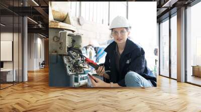 Female electrician worker checking, repair, maintenance operation electric system of robotic arm in factory. Electrician using electrical meters working with operation electric system of robot arm Wall mural