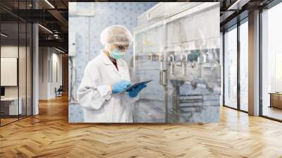 Female worker produces inspecting quality of plastic water tank on conveyor belt in drinking water factory. Worker using tablet working and checking bottle or gallon on conveyor production line Wall mural