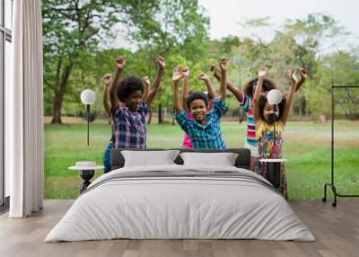 Group of African American children playing and raising their hands in the park. Cheerful diverse black children dancing together outdoor Wall mural