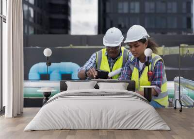 Group of African American engineer worker working in sewer pipes area at construction site. Male engineer and woman engineer work with laptop computer for maintenance sewer pipes Wall mural