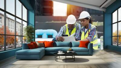 Group of African American engineer working in sewer pipes area at construction site. Male engineer and woman engineer discussing for maintenance sewer pipes, water tank on rooftop of building Wall mural