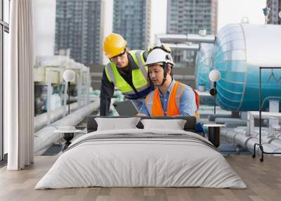 Group of Asian male engineer working at construction site area. Male engineer worker standing near sewer pipes or water tank area. Team of male plumber worker maintenance sewer pipes network system Wall mural