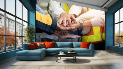 Group of male and female factory workers standing putting their hands together in industry factory. Factory workers stack of hands in factory. Unity and teamwork concept Wall mural