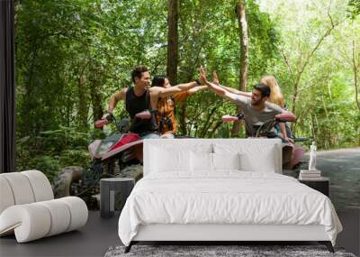 Group of young man and woman driving off road adventure with happy and smiling. Friends riding on ATV bike or quad bike on road along forest trail on mountain. Camping, jungle adventure concept Wall mural