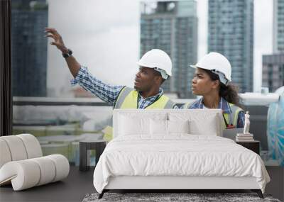 Male and female engineer worker working with laptop computer discuss and inspecting structure of building at rooftop of building at construction site Wall mural