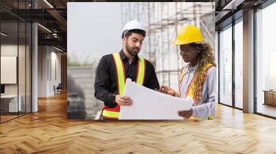 Male and female foreman builder working together at construction site. Male engineer construction working at construction site. Female engineer working at construction site Wall mural