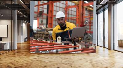 Male engineer factory worker control CNC machine by laptop computer in industry factory. Male worker working and control conveyor in manufacturing process in factory Wall mural