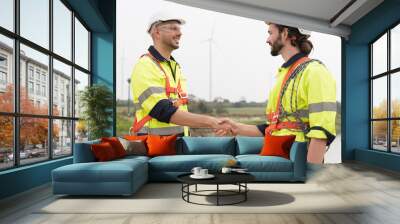 Male engineer join hand together at windmill field farm, wearing safety uniform and working and inspecting quality of wind turbines, repairing or maintenance wind turbines Wall mural