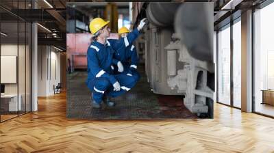 Male engineer worker maintenance locomotive engine, wearing safety uniform, helmet and gloves in locomotive garage. Male railway engineer repair railhead engine in garage Wall mural