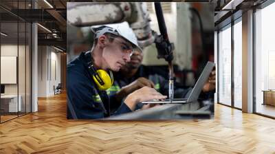 Male engineer worker working with computer notebook for control automatic robotic arm machine in the factory. Male technician worker maintenance automatic robotic hand in smart factory Wall mural