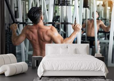 Muscular young man exercising with weight lifting machine in the fitness gym Wall mural