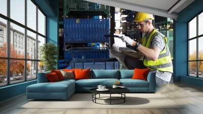 Storage warehouse and manufacturing concept. Male warehouse worker working with laptop computer and inspecting quality for auto spare parts at warehouse Wall mural