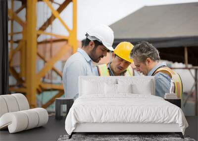 Team of male engineer construction working and discussing of structure of building at construction site. Group of male construction builder working at construction site Wall mural