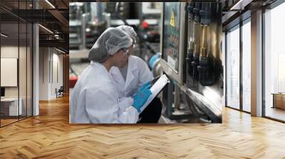 Two female worker wearing uniform, hairnet working and checking of water pump system, pipes station, Water pressure system, water tank at production line in industry factory Wall mural