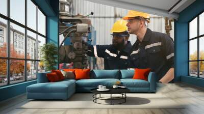 Two male engineer workers working with metal lathe machine at production line in factory, wearing safety uniform, helmet and protective gloves Wall mural