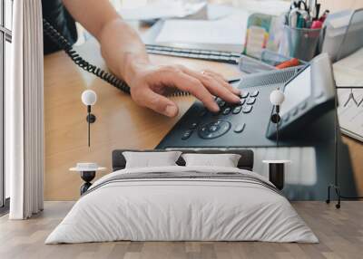 Left-handed man's hand dialing the office telephone Wall mural