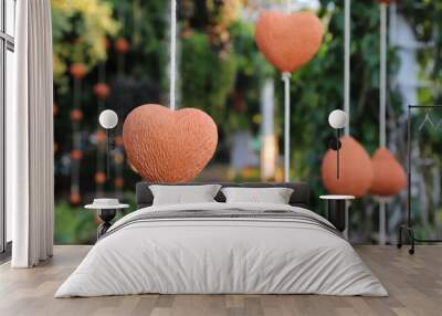 Closeup of brown heart-shape handmade earthenware hanging by white rope. Wall mural