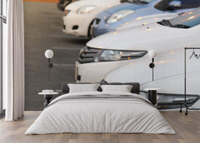 Closeup of front side of white car and other cars parking in outdoor parking area in twilight evening. Vertical view. Wall mural