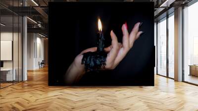 Black Candle melted on hand in black background. For halloween's concept. Felling darkness with light of flame burning from the supernatural. Wall mural