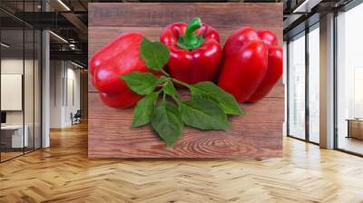 Red fresh bell peppers and leaves on old rustic table Wall mural