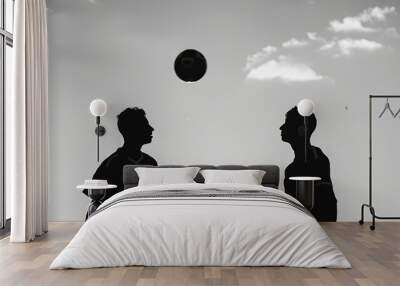 Two children in a black and white portrait looking at a ball bouncing above their heads. Wall mural