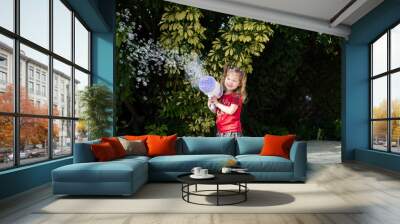 Little happy Caucasian girl playing with a bubble gun. Bubble machine fun. Best toy for small kids. Summer fun concept Wall mural