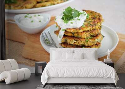 vegetable fritters, vegetarian pancakes, served in a pile on a white plate with sour cream and fresh herbs. Wall mural