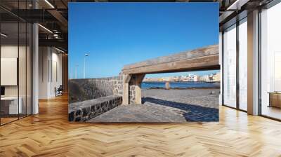 Views of El Medano town framed by a narrow wooden gangway and cobblestone pathways, towards the bay and residences behind, hotels and restaurants, beaches and coast, in Tenerife, Canary Islands, Spain Wall mural