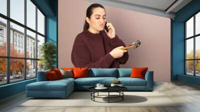 Helpless woman holding tools talking on phone Wall mural