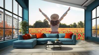 Young woman dancing on poppy field from back Wall mural