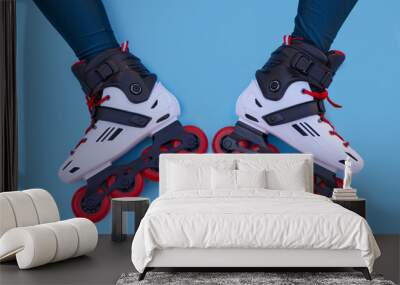 Two legs of a girl with inline skates facing each other on a blue background with copyspace Wall mural