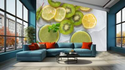 Healthy fresh fruit smoothie drink surrounded by kiwi lime and lemon on a gray concrete background. The concept of a healthy lifestyle and proper nutrition. Vitamin drink. Wall mural