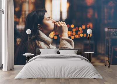 A young woman is sitting with her hands folded and is praying in a church Wall mural