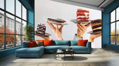 Concept for cafe or bakery with desserts: plates with different cakes in people's hands, place for your text Wall mural