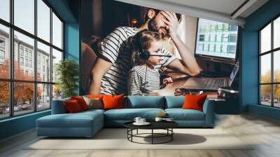 Father and daughter are working on a laptop. businessman working from home and watching the child. A young man works on a computer. Launch. Freelancer concept. Family on quarantine Wall mural