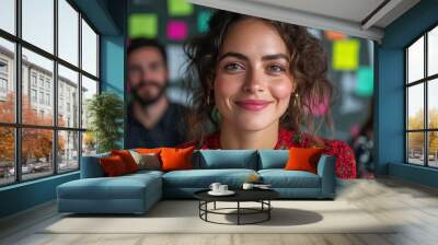 Portrait of a confident woman smiling in a vibrant, creative office setting, with colleagues in the blurred background. Wall mural