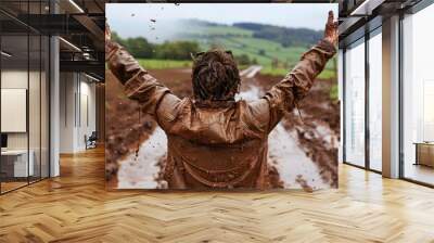 Person standing victoriously on a muddy mountain top their face and clothes reflecting hard work Stock Photo with copy space Wall mural