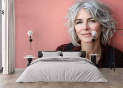 Western elderly woman dabbing eye cream under her eyes, smiling warmly at the camera, isolated on a pastel pink background Stock Photo with side copy space Wall mural